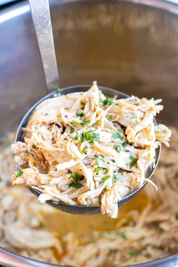 A ladle full of shredded salsa chicken from an Instant Pot bowl.