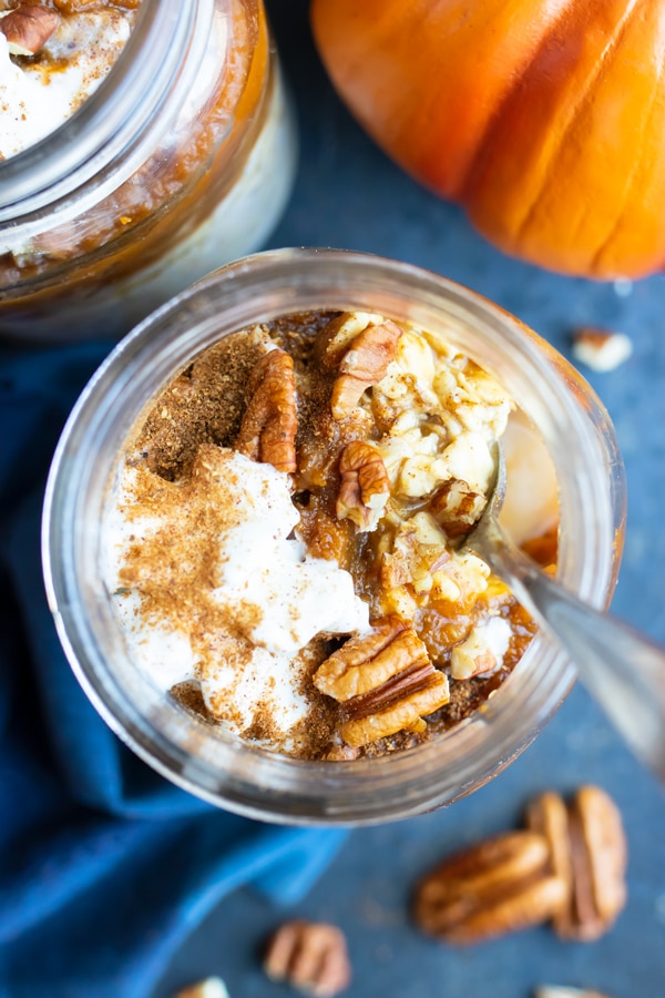 Healthy vegan and gluten-free overnight oats with toasted pecans next to a pumpkin.