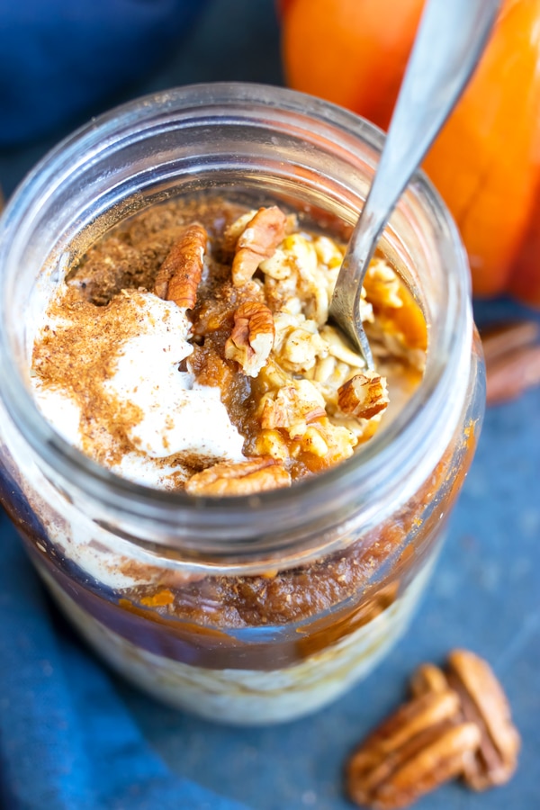 A spoon getting a bite of the best overnight oats from a glass mason jar.