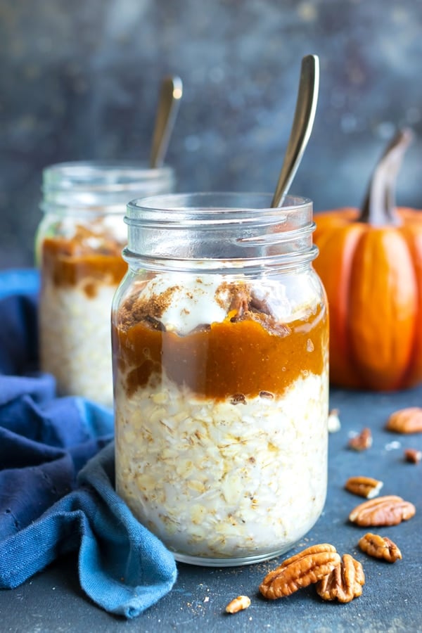 Two glass jars full of healthy pumpkin overnight oats recipe with pecans next to them.