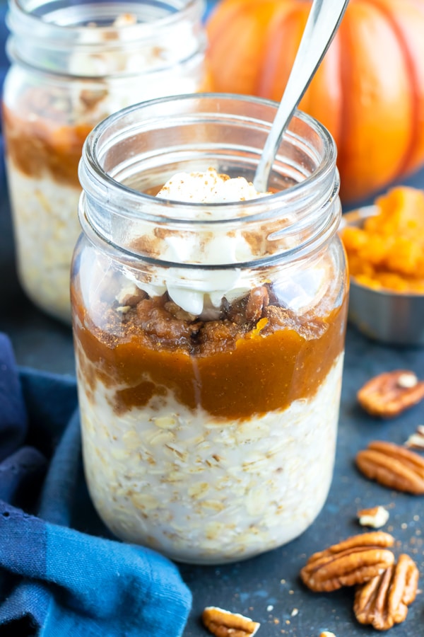 Two mason jars full of easy vegan pumpkin pie overnight oats recipe with pecans next to them.