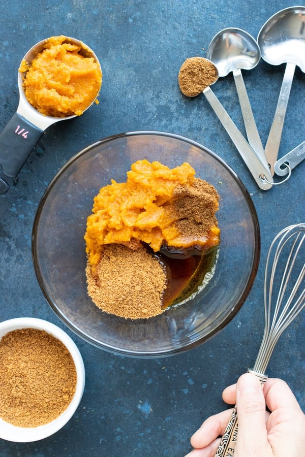 Pumpkin puree, coconut sugar, maple syrup, and pumpkin pie spice being mixed together for an easy overnight oats recipe.