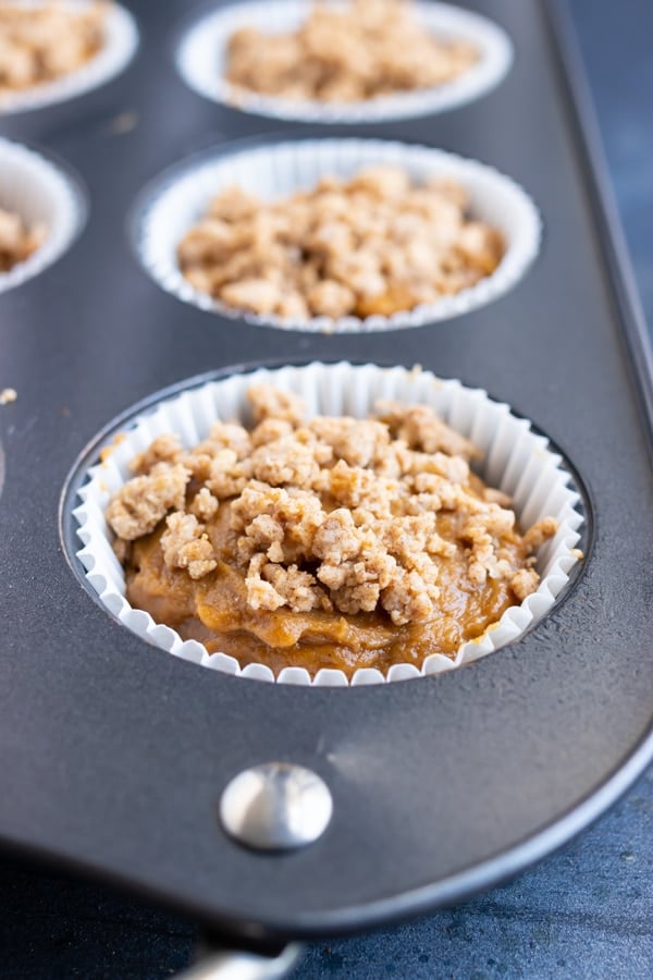 Streusel muffins with white cupcake liners in a muffin tray.