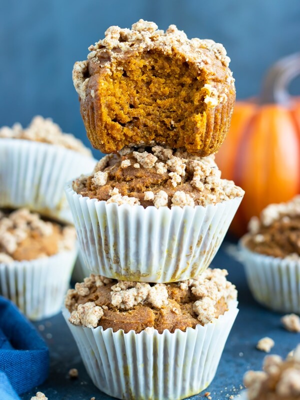 Three gluten-free pumpkin muffins stacked on top of each other surround by other healthy, vegan, and easy pumpkin muffins.