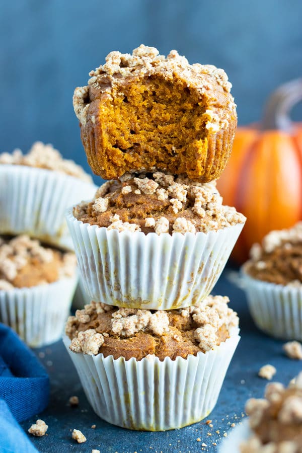 Three gluten-free pumpkin muffins stacked on top of each other surround by other healthy, vegan, and easy pumpkin muffins.