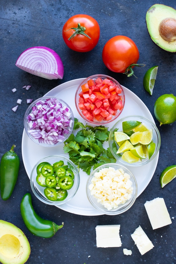 Red onion, tomatoes, cilantro, cheese, and lime juice as toppings for shredded chicken tacos.