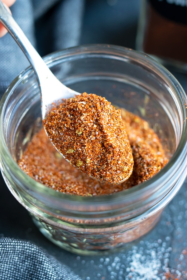 A spoon picking up chili seasoning mix to put into a homemade Instant Pot chili recipe.