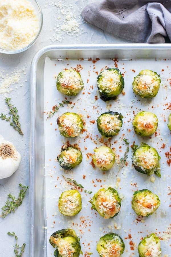 Crispy smashed Brussels sprouts with garlic and Parmesan cheese on a large baking sheet that have roasted in the oven.
