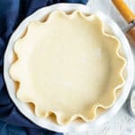 A white 9-inch pie plate full of gluten-free dough.