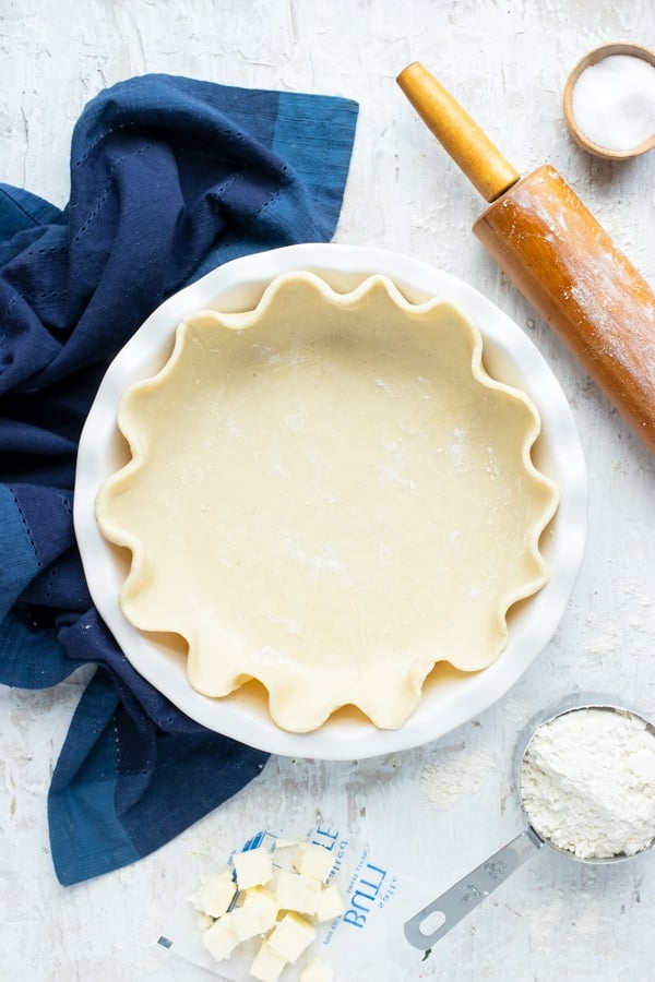 A white 9-inch pie plate full of crust dough.