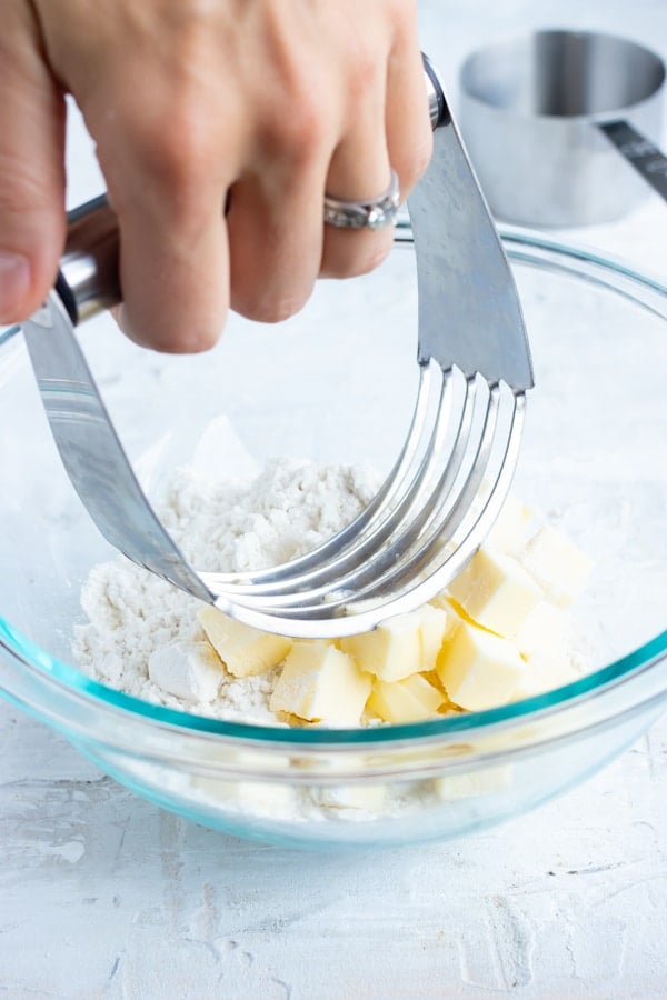 A pastry cutter mixing together cold butter and flour for an easy pie crust recipe.