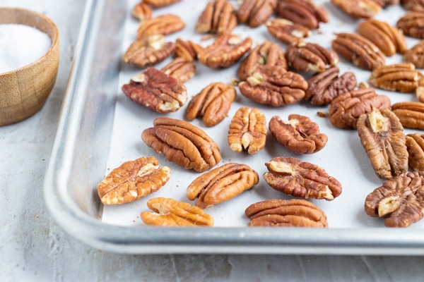 Toasted pecans on a baking sheet with parchment paper.