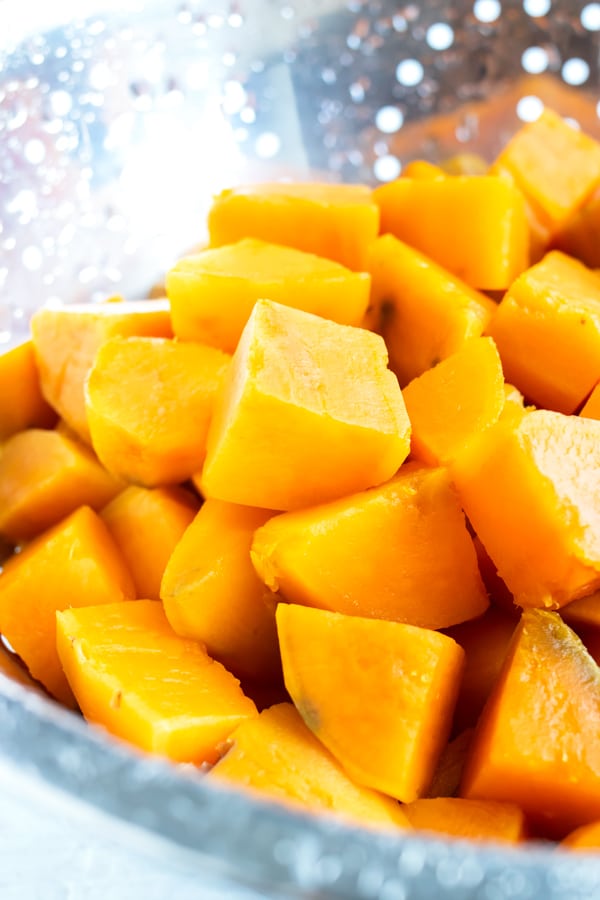 Boiling sweet potatoes and draining in a colander for a sweet potato mash recipe.