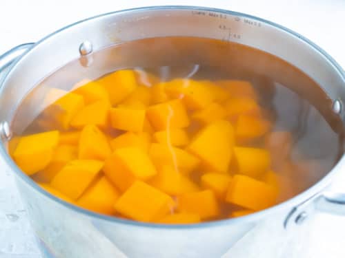 A pot of water full of orange potatoes showing how to boil sweet potatoes.