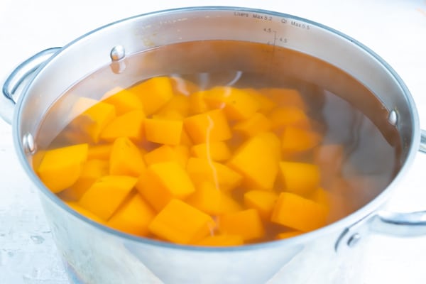 A pot of water full of orange potatoes showing how to boil sweet potatoes.