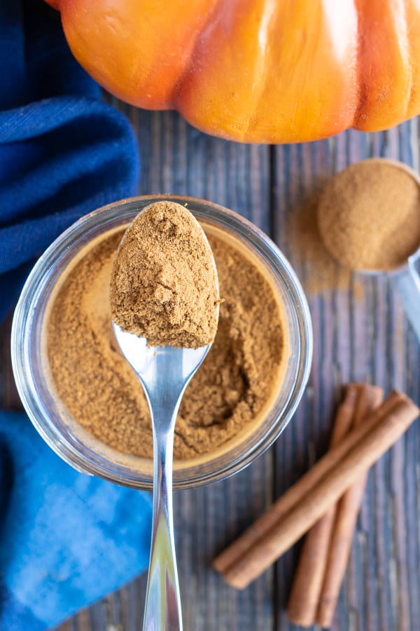 A spoon scooping out a teaspoon of homemade pumpkin pie spice.