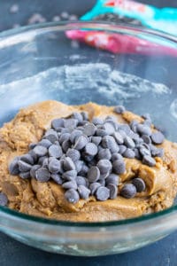 Chocolate chips being added to cookie dough.