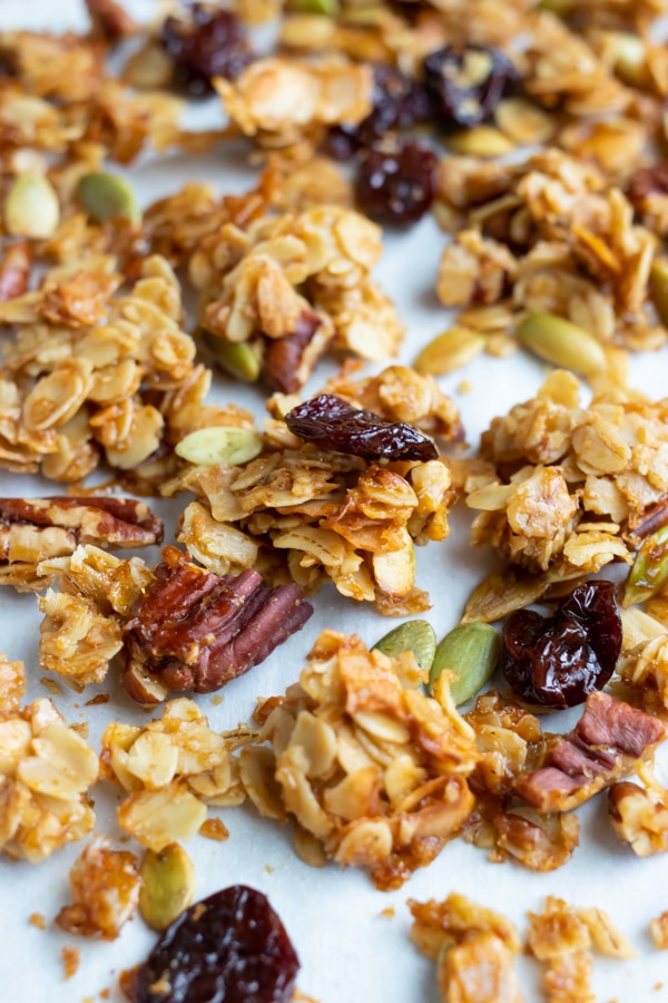 Big clusters of granola on a parchment paper lined baking sheet.
