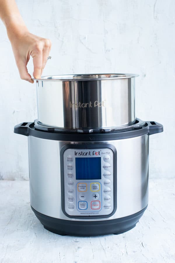 A stainless steel pot being placed into an electric pressure cooker.