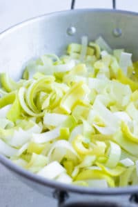 A colander full of thinly sliced and cleaned leeks for a potato leek soup recipe.