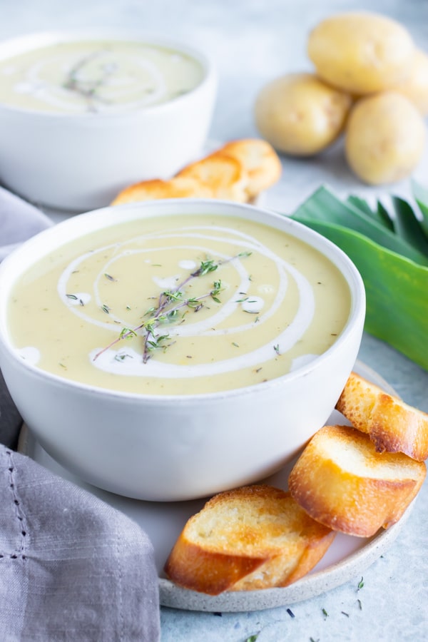A quick, easy, and healthy potato leek soup recipe that is being served with toasted baguettes.