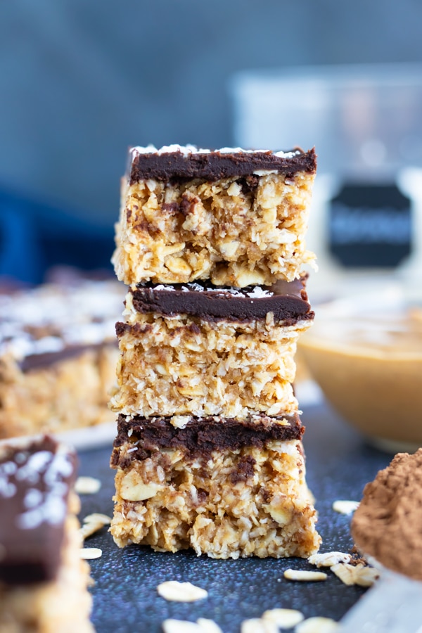 No-bake Samoa Cookie Oatmeal bars in a stack next to a bowl of peanut butter.