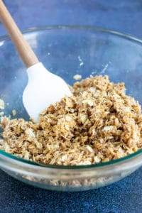 A large glass bowl with no-bake oatmeal ingredients being mixed together with a spatula.