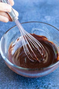 Healthy, vegan, chocolate glaze being mixed together in a glass bowl.