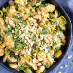 A bowl full of roasted Brussels sprouts with a peanut butter sauce and cilantro.