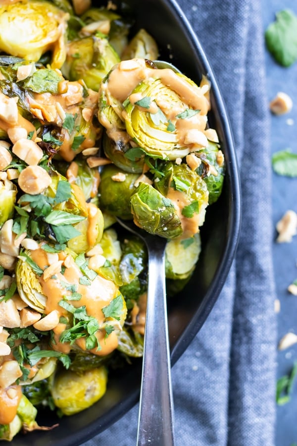 A close-up of a serving spoon full of roasted and shredded Brussels sprouts.