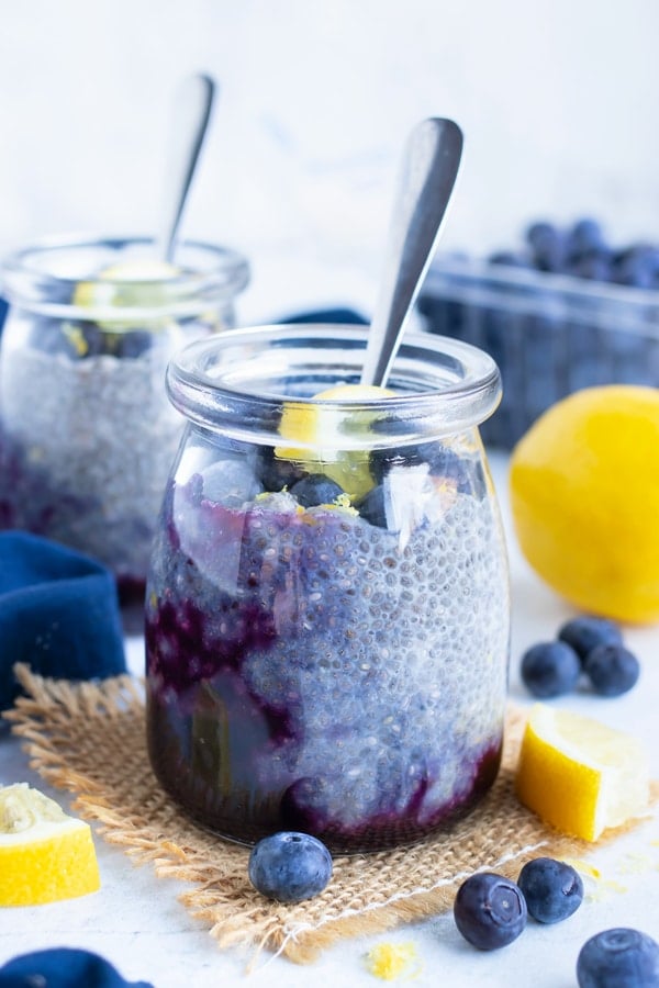 Blueberry lemon chia seed pudding in a clear glass jar next to a pint of blueberries.