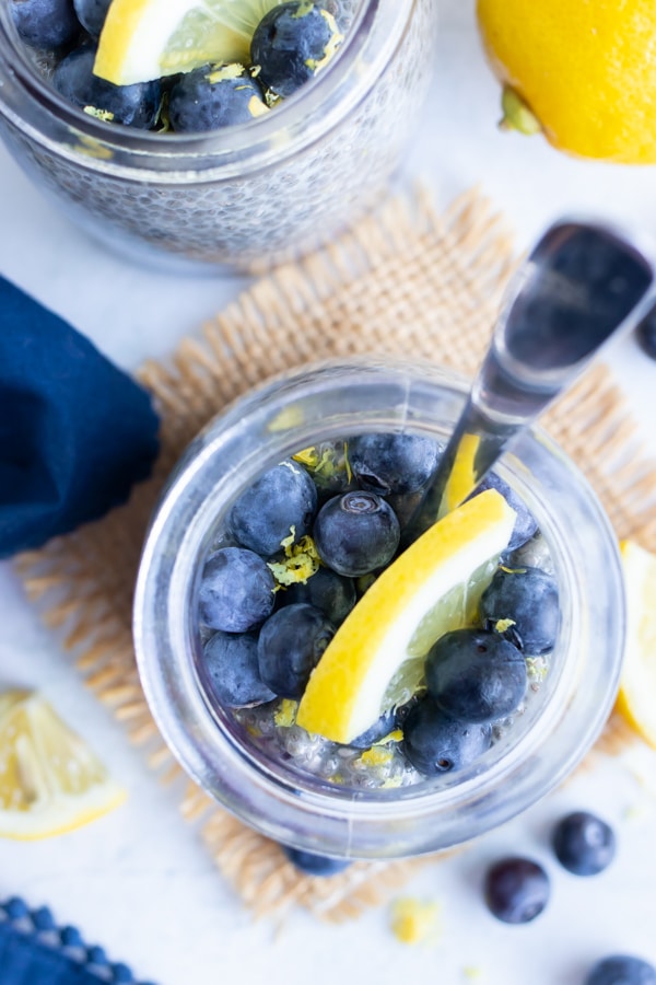 Blueberries and a lemon slice in a small glass jar with a spoon.