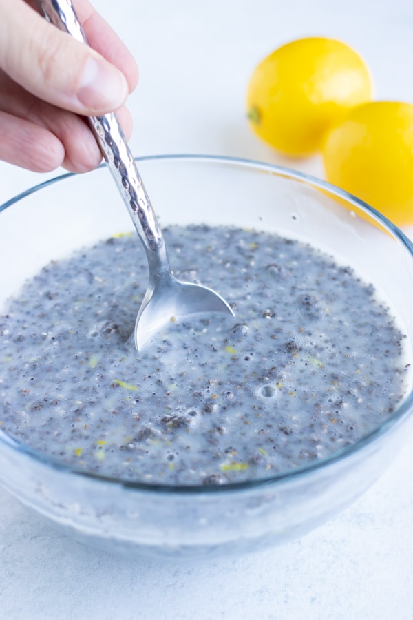 Black chia seeds and milk being mixed together in a glass bowl.