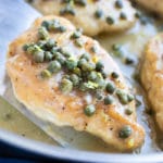 Lemon Chicken Piccata with capers and a creamy sauce in a skillet.