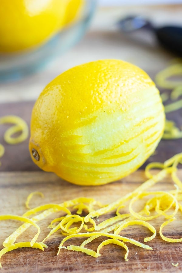 A lemon showing the pith and the peel after being zested with a citrus zester.