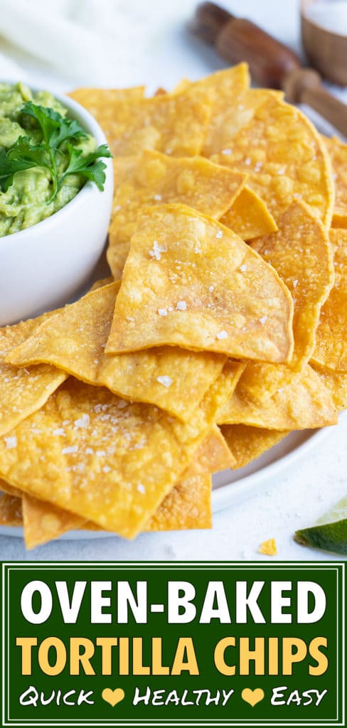 Homemade tortilla chips on a white plate next to a bowl of guacamole.