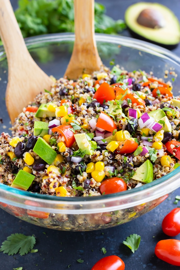 A Mexican Quinoa Salad with avocado in a clear glass bowl with a cilantro lime dressing.
