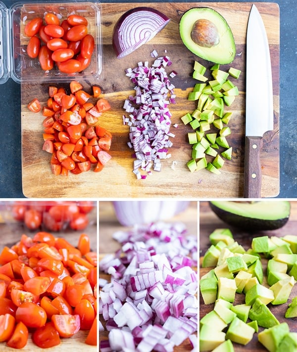 Chopped tomatoes, red onion, and avocado on a wooden cutting board.