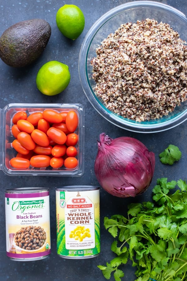 Cooked quinoa, avocado, tomatoes, beans, corn, and cilantro for a salad recipe.