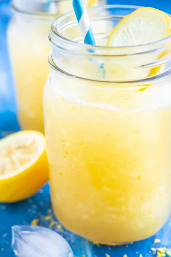 A glass full of a yellow icey drink made with lemons, sugar, and water.