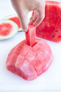 Pulling a small chunk from half of a cut watermelon