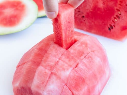 Pulling a small chunk from half of a cut watermelon