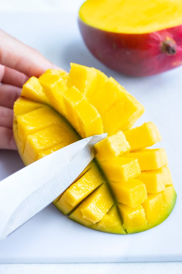 Removing mango pieces with a knife.