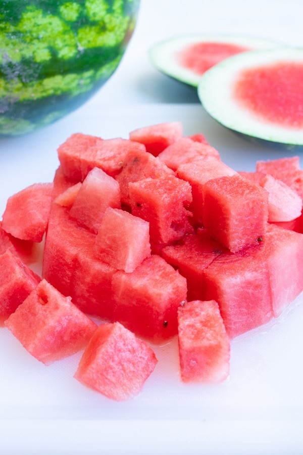A stack of seedless cubed watermelon on a cutting board.