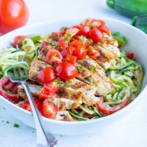Cajun chicken zoodles in a bowl are topped with sliced fresh tomatoes for an easy, low carb meal.