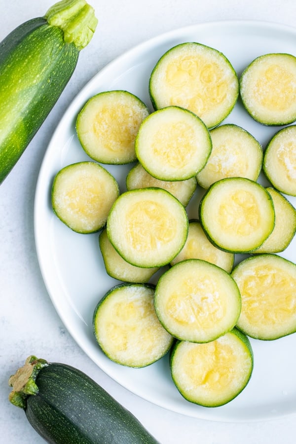 Frozen zucchini is stacked on a white plate on the counter.
