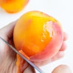 Using a paring knife, peel back the skin of the peach in your hand.