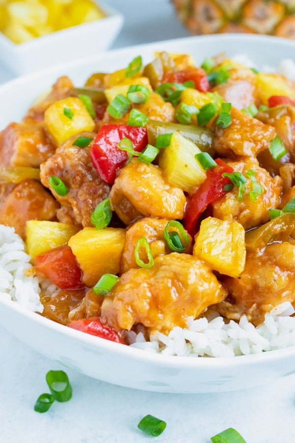 Healthy pressure cooker Pineapple Chicken is loaded with pineapple, bell peppers, and fresh green onions and laid over a rice.