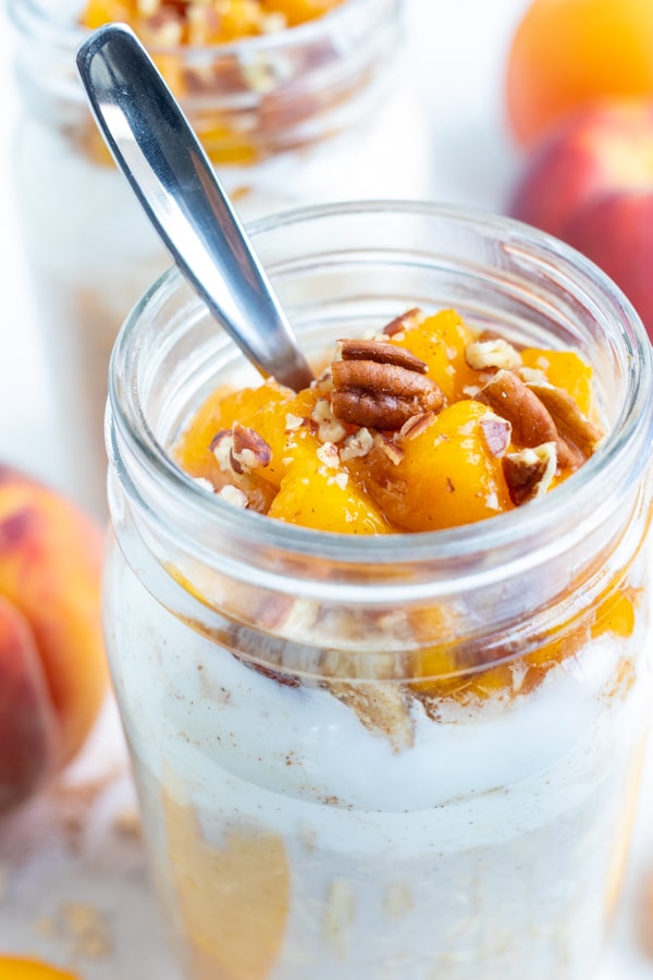 Peach oatmeal is made with yogurt, oats, and fresh peeled and sliced peaches and topped with toasted pecans for a delicious cobbler-like flavor.