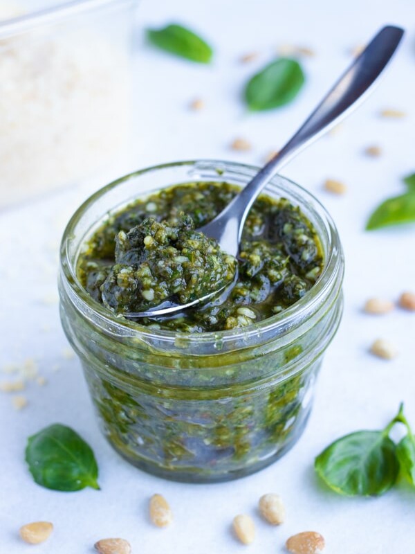A small mason jar holds fresh, basil pesto sauce that can be used on chicken or pasta dishes.